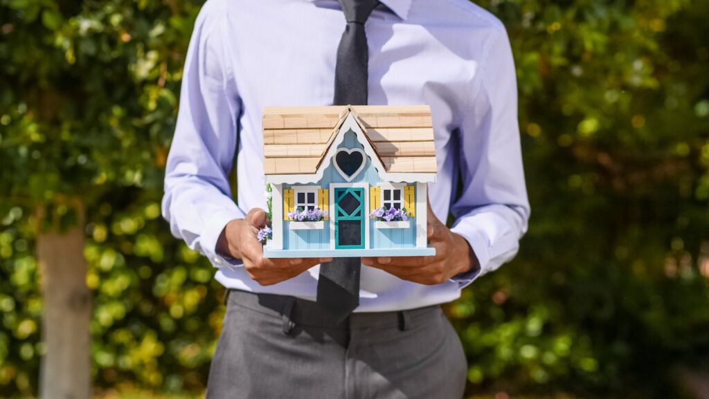 person holding a miniature house